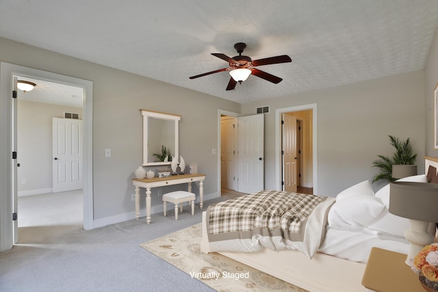 bedroom featuring ceiling fan, light colored carpet, and a textured ceiling