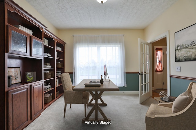 carpeted office space with a textured ceiling and french doors