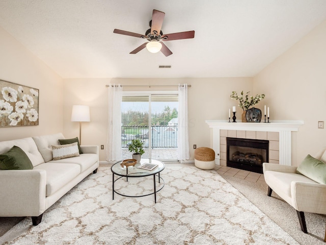 living room with carpet flooring, a tiled fireplace, ceiling fan, and lofted ceiling