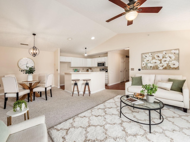 living room featuring ceiling fan with notable chandelier, sink, lofted ceiling, and light carpet