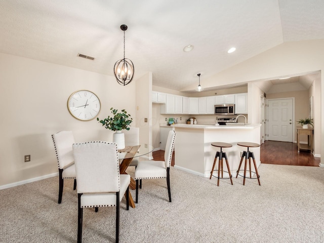 dining room featuring a chandelier, hardwood / wood-style floors, and vaulted ceiling