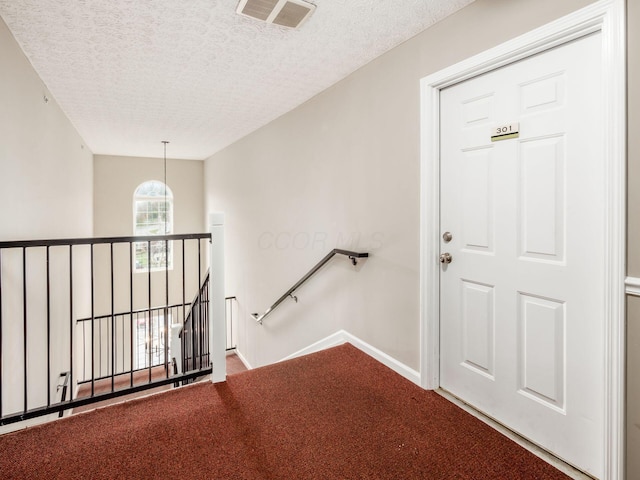 stairs featuring carpet flooring and a textured ceiling