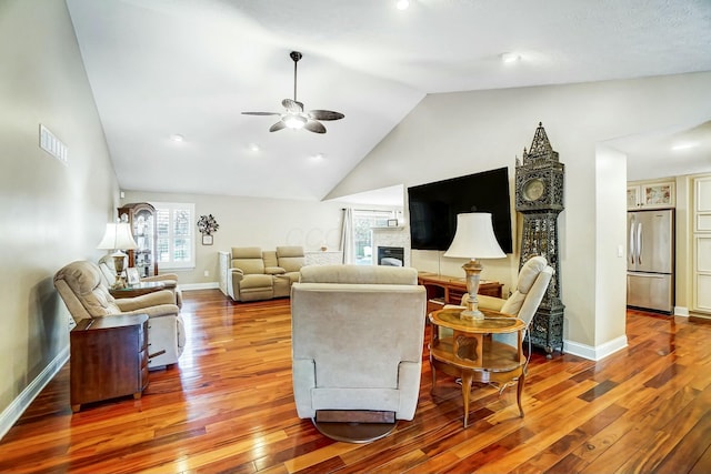 living room with hardwood / wood-style flooring, ceiling fan, and high vaulted ceiling