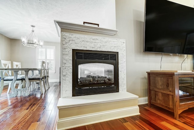 interior details with hardwood / wood-style floors, a notable chandelier, a multi sided fireplace, and a textured ceiling