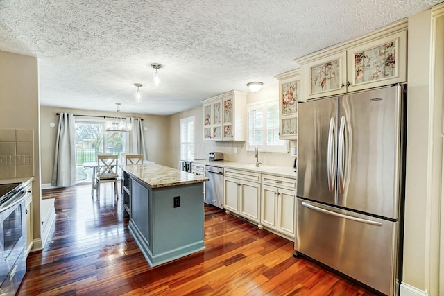 kitchen featuring a center island, hanging light fixtures, dark hardwood / wood-style floors, light stone countertops, and stainless steel appliances