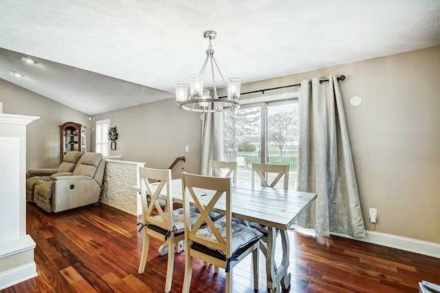 dining room with dark hardwood / wood-style floors, a textured ceiling, a chandelier, and vaulted ceiling