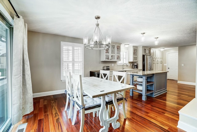 dining room with a notable chandelier, dark hardwood / wood-style floors, sink, and a textured ceiling