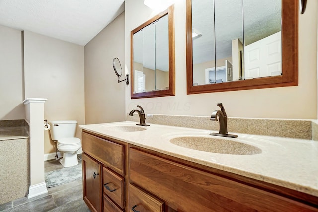 bathroom with vanity, toilet, and a textured ceiling