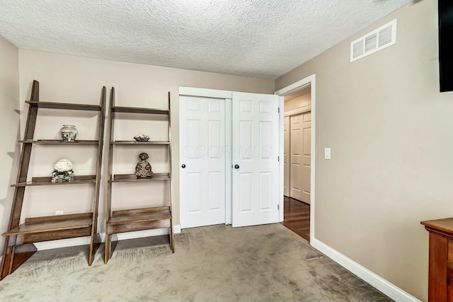 carpeted bedroom featuring a closet and a textured ceiling