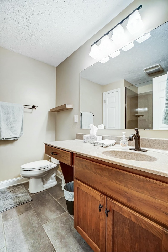 bathroom featuring a textured ceiling, vanity, toilet, and walk in shower