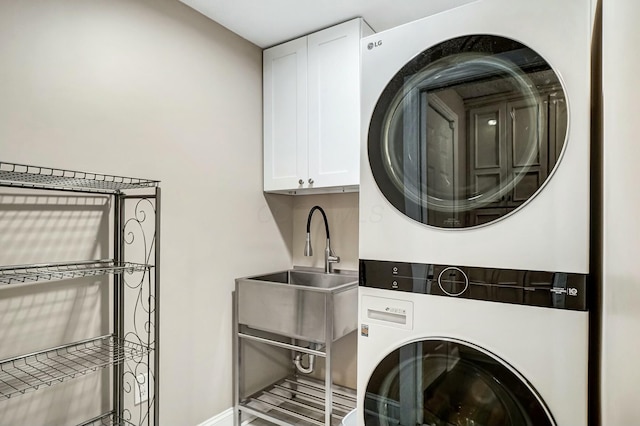 clothes washing area with stacked washer and dryer, cabinets, and sink