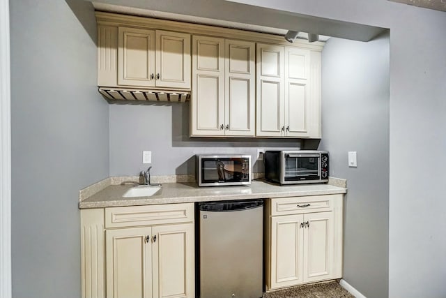 kitchen with cream cabinets, sink, and fridge