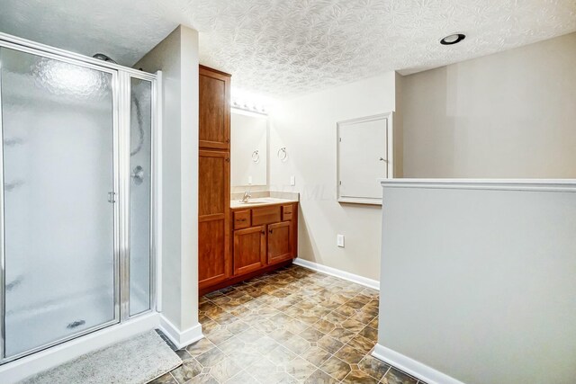 bathroom featuring a textured ceiling, vanity, and a shower with shower door