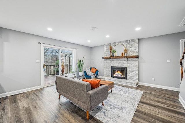 living room featuring dark wood-type flooring and a brick fireplace