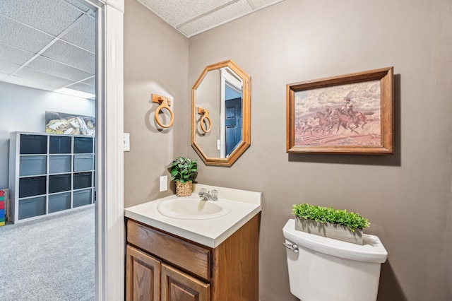 bathroom with a drop ceiling, vanity, and toilet