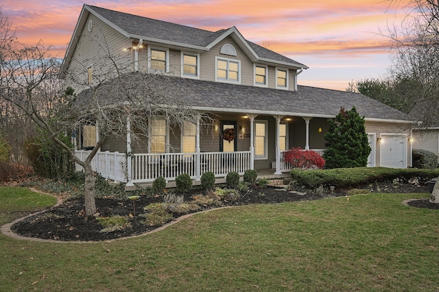 view of front of house with a yard, a porch, and a garage