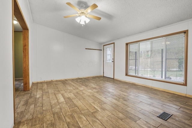 spare room with a textured ceiling, light wood-type flooring, and ceiling fan