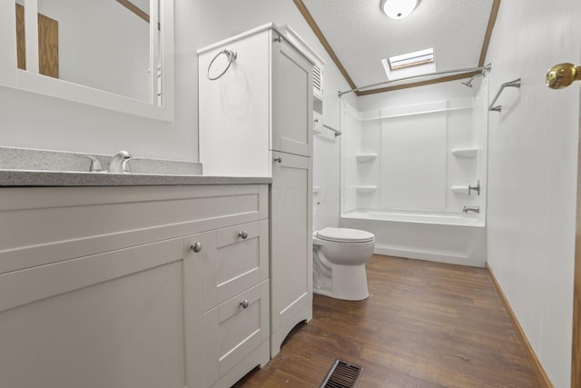 full bathroom featuring a skylight, a textured ceiling, shower / washtub combination, hardwood / wood-style floors, and toilet