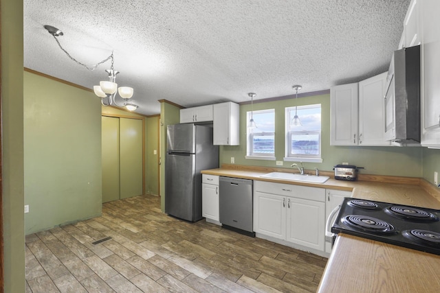 kitchen featuring a textured ceiling, stainless steel appliances, sink, decorative light fixtures, and white cabinets