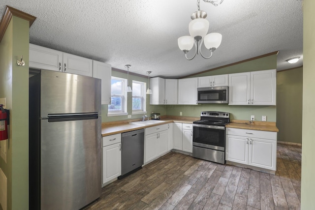 kitchen featuring appliances with stainless steel finishes, decorative light fixtures, white cabinets, dark hardwood / wood-style floors, and lofted ceiling