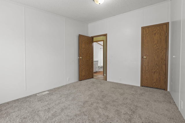 unfurnished room with carpet and a textured ceiling