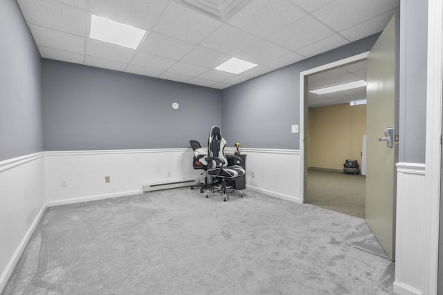 interior space with carpet flooring, a drop ceiling, and a baseboard heating unit