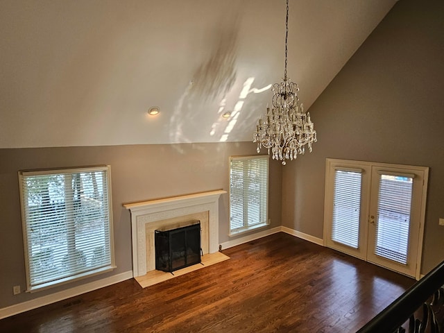 unfurnished living room featuring hardwood / wood-style floors, vaulted ceiling, a notable chandelier, and a premium fireplace