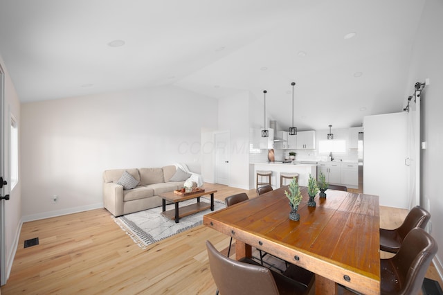 dining room featuring sink, lofted ceiling, and light wood-type flooring