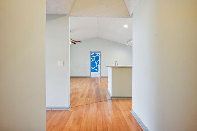 corridor with hardwood / wood-style floors, vaulted ceiling, and sink