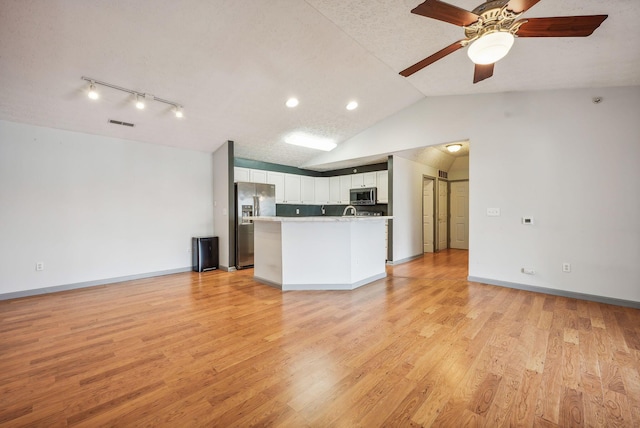 kitchen with white cabinetry, light hardwood / wood-style flooring, a textured ceiling, lofted ceiling, and appliances with stainless steel finishes