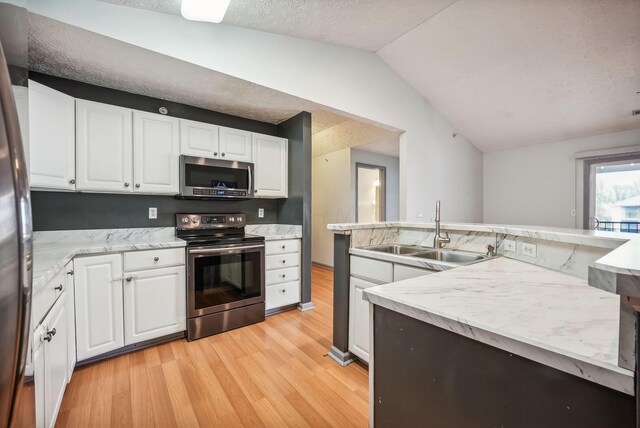 kitchen with sink, stainless steel appliances, light hardwood / wood-style floors, vaulted ceiling, and white cabinets