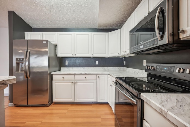 kitchen with white cabinets, a textured ceiling, appliances with stainless steel finishes, and light hardwood / wood-style flooring