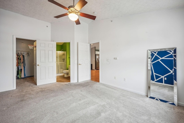 unfurnished bedroom with ceiling fan, high vaulted ceiling, carpet floors, a walk in closet, and a closet