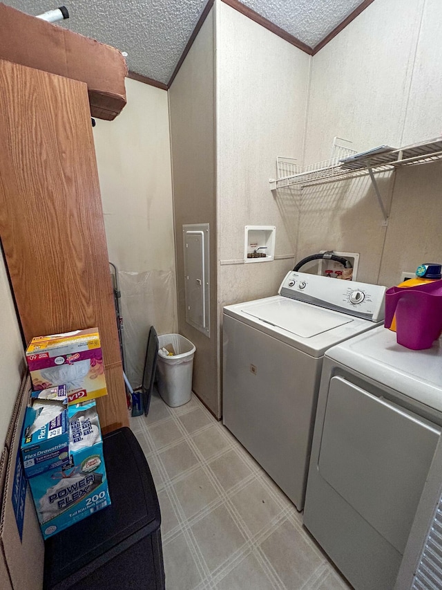 laundry room with a textured ceiling, separate washer and dryer, ornamental molding, and electric panel