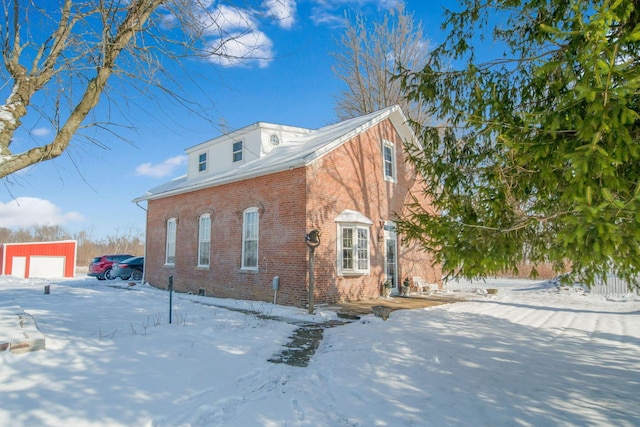 snow covered property featuring a garage and an outdoor structure