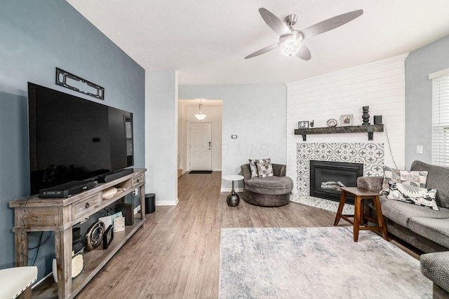 living room featuring hardwood / wood-style floors, ceiling fan, and a tiled fireplace