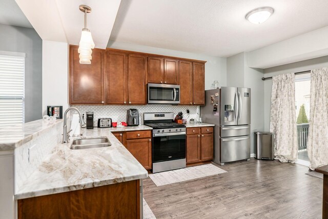 kitchen featuring pendant lighting, hardwood / wood-style floors, sink, tasteful backsplash, and stainless steel appliances