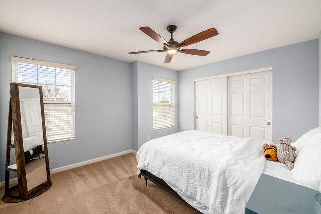 carpeted bedroom with ceiling fan, a closet, and multiple windows