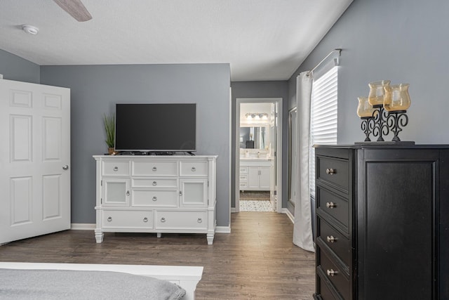 bedroom with a textured ceiling, dark hardwood / wood-style floors, ensuite bath, and ceiling fan