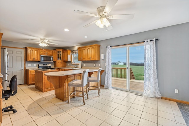 kitchen featuring appliances with stainless steel finishes, a kitchen breakfast bar, sink, light tile patterned floors, and a kitchen island