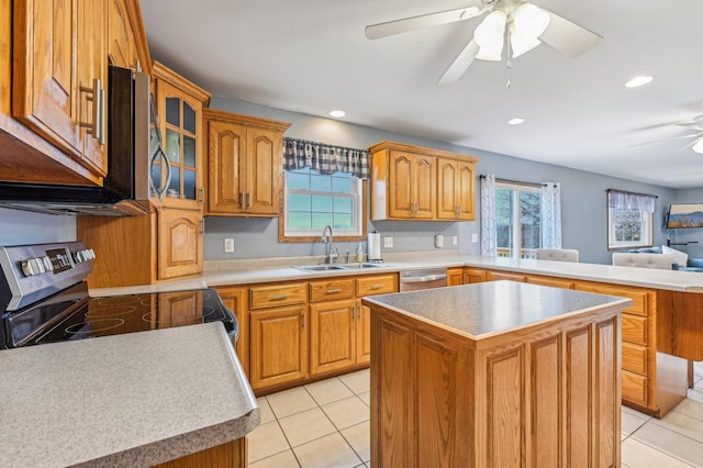 kitchen with sink, light tile patterned floors, appliances with stainless steel finishes, a kitchen island, and kitchen peninsula