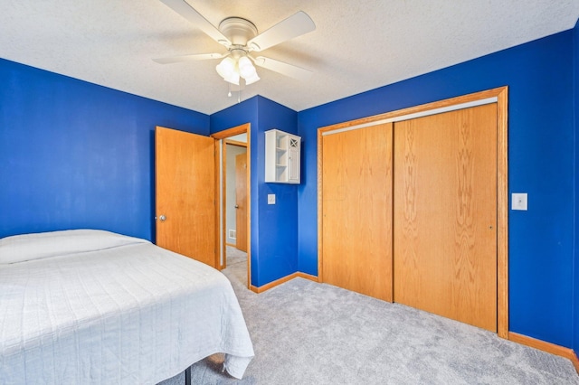 unfurnished bedroom featuring ceiling fan, light colored carpet, a textured ceiling, and a closet