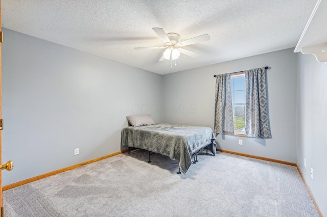 bedroom featuring a textured ceiling, light colored carpet, and ceiling fan