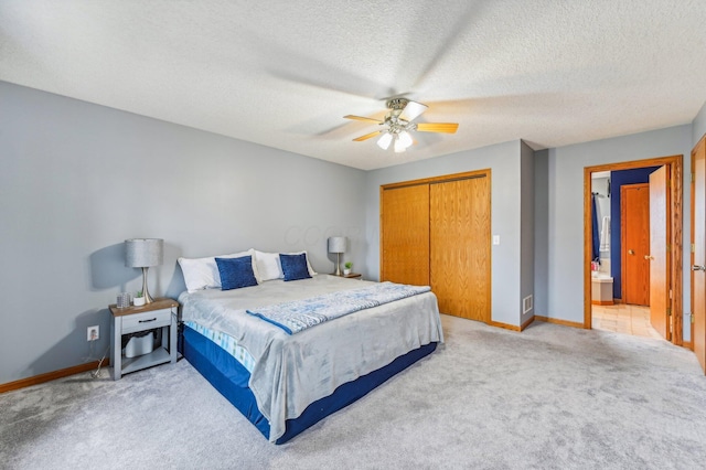 carpeted bedroom featuring a textured ceiling, a closet, ceiling fan, and connected bathroom