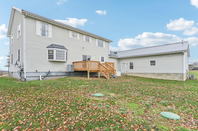 rear view of property featuring a lawn, central AC unit, and a deck