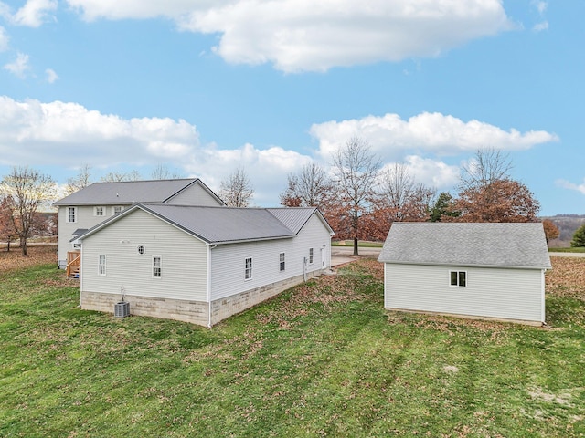 view of side of home with central AC unit and a yard