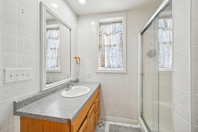 bathroom featuring an enclosed shower, vanity, tile patterned floors, and tile walls