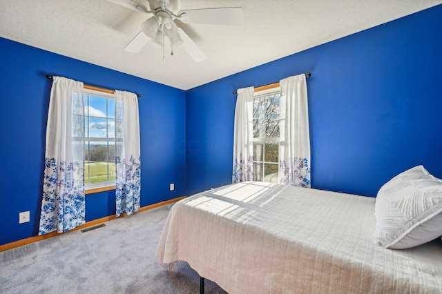 unfurnished bedroom with multiple windows, ceiling fan, carpet floors, and a textured ceiling