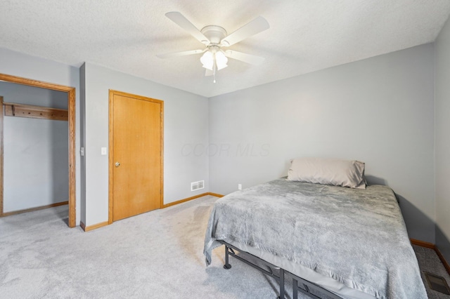 carpeted bedroom featuring ceiling fan, a closet, and a textured ceiling