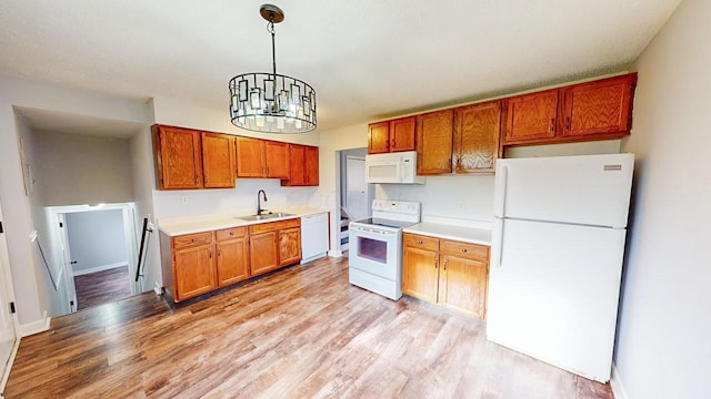 kitchen with white appliances, an inviting chandelier, sink, light wood-type flooring, and decorative light fixtures